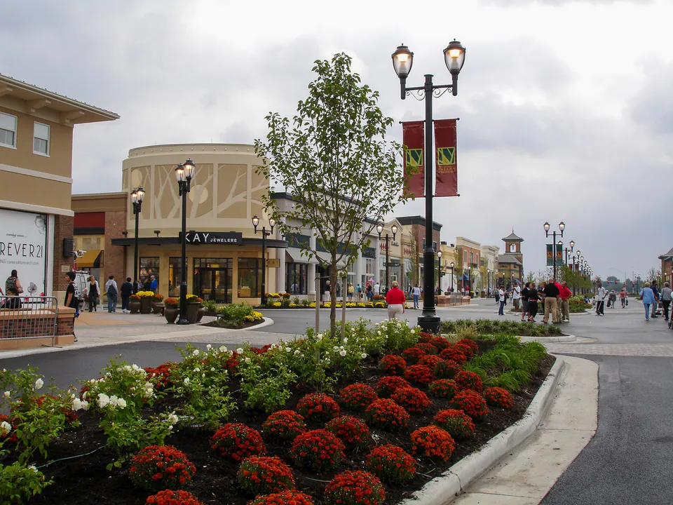 Maintained retail streetscape with seasonal color, clean bed edges, street trees, and pedestrian circulation